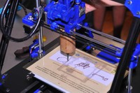 Detalle de una impresora 3D reproduciendo unas firmas en chocolate