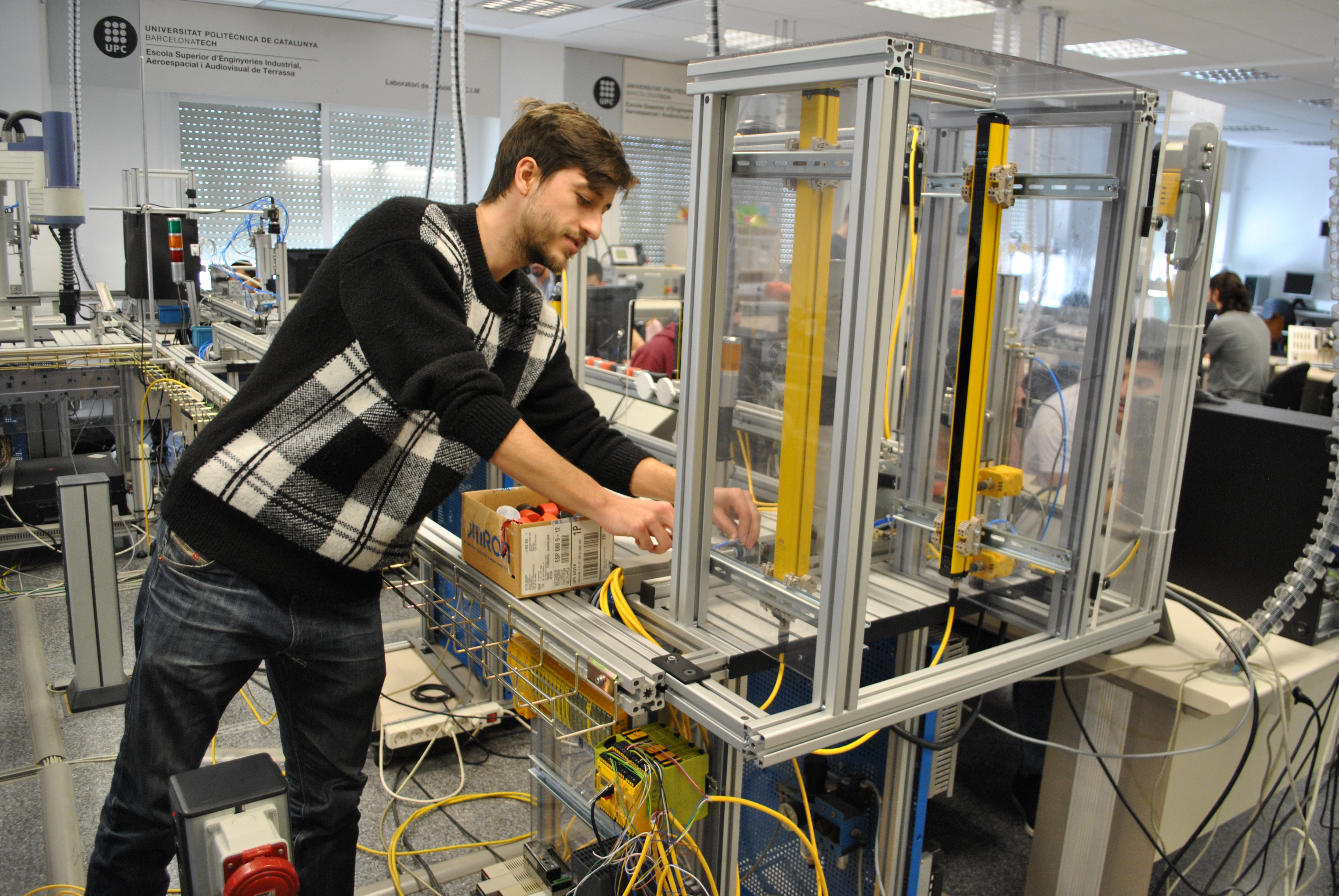 estudiant de l’eseiaat fent pràctiques al laboratori  de robòtica i cim  amb l’equip de seguretat factory 4.0 de pilz